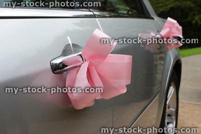 Stock image of silver chauffeured limousine decorated with pink ribbon, wedding car bows