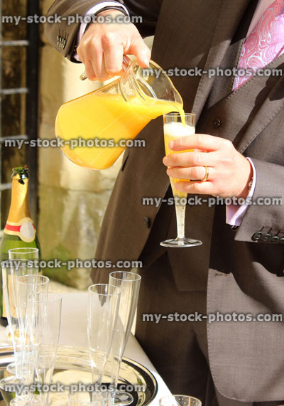 Stock image of bridegroom pouring orange juice at wedding, champagne glass / flute, bucks fizz