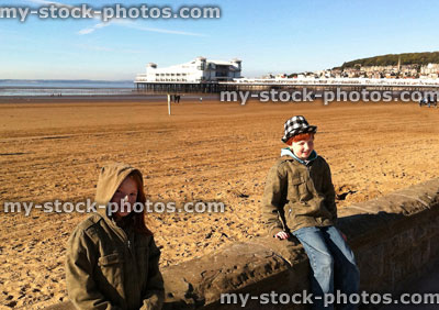 Stock image of Children sat on a wall at the beach
