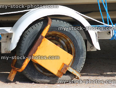 Stock image of yellow wheel clamp locking vehicle, parking fine