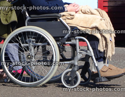 Stock image of disabled man being pushed in wheelchair by carer