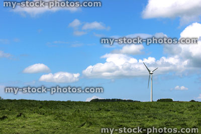 Stock image of wind turbine windmill in field, blue sky, clouds