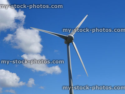 Stock image of wind turbine windmill blades spinning, generating wind power electricity