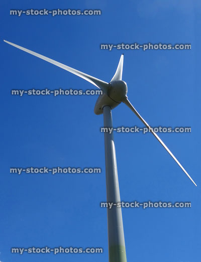 Stock image of wind turbine windmill against cloud free sky, blot on the landscape
