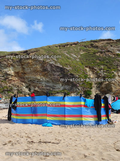 Stock image of sandy beach with striped seaside windbreak against cliff