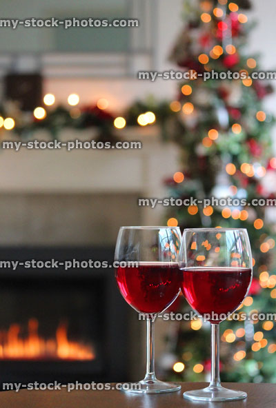 Stock image of two red wine glasses, gas fire, fairylights and Christmas tree