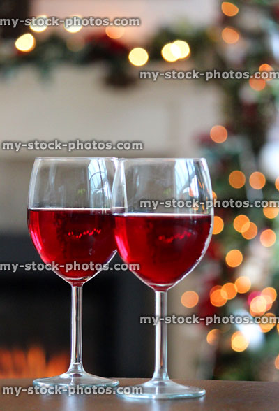 Stock image of red wine in glasses at Christmas, fireplace, fairylights