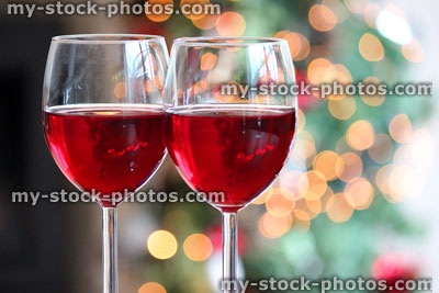 Stock image of two glasses with red wine, blurred Christmas tree fairylights