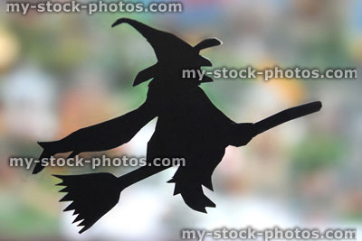 Stock image of black witch silhouette, flying broomstick, blurred background leaves, halloween background