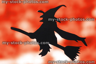 Stock image of black witch silhouette, flying broomstick, fiery autumn leaves, halloween background