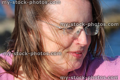 Stock image of woman enjoying sunshine, pink top, rimless glasses