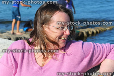 Stock image of woman enjoying sunshine, pink top, rimless glasses