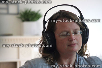 Stock image of woman listening to music on large headphones, eyes closed