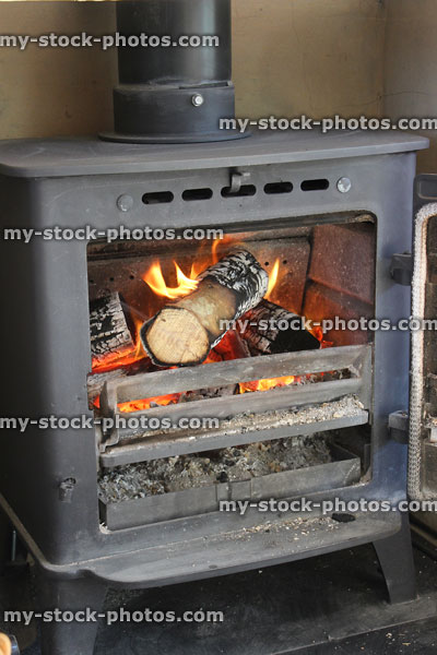 Stock image of roaring fire inside metal woodburner stove fireplace, door open