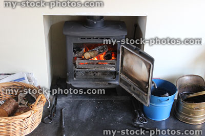 Stock image of contemporary fireplace with iron wood burning stove, log basket