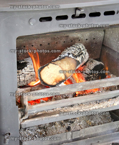 Stock image of wood burning multi fuel stove with burning logs, flames / fireplace