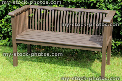 Stock image of formal wooden garden bench on lawn, garden seat