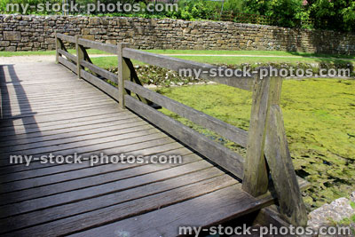 Stock image of wooden bridge leading to ancient castle ruins, over surrounding moat