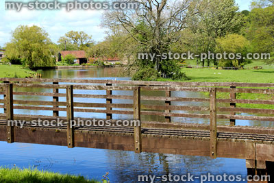 Stock image of wooden bridge with handrails in countryside, across stream