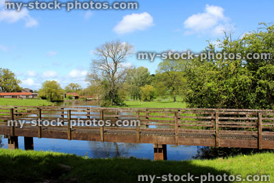 Stock image of wooden bridge spanning stream in countryside, by farm
