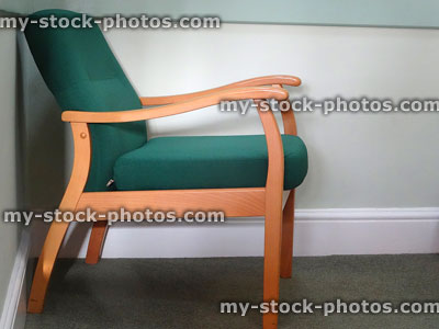Stock image of wooden chair, doctor's waiting room, green cushioned seat