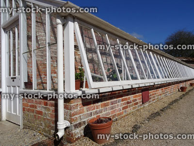 Stock image of white wooden greenhouse / glasshouse with brick wall base