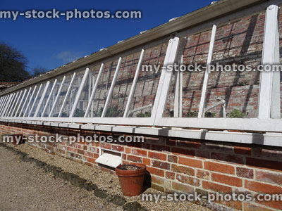 Stock image of wooden greenhouse / glasshouse painted white, glass windows, brick base
