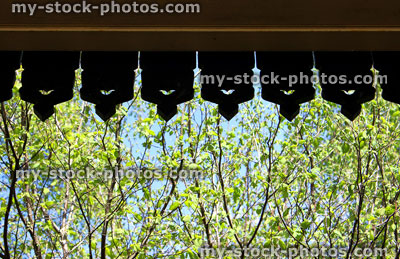 Stock image of ornate wooden edging to roof against garden background
