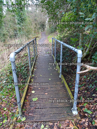 Stock image of woodland bridge with metal handrails, wooden decking chicken wire