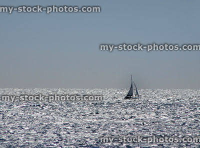 Stock image of single yacht sailing on sparkling blue sea waves