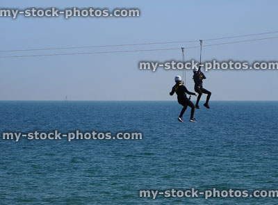 Stock image of children on seaside zip line over sea water